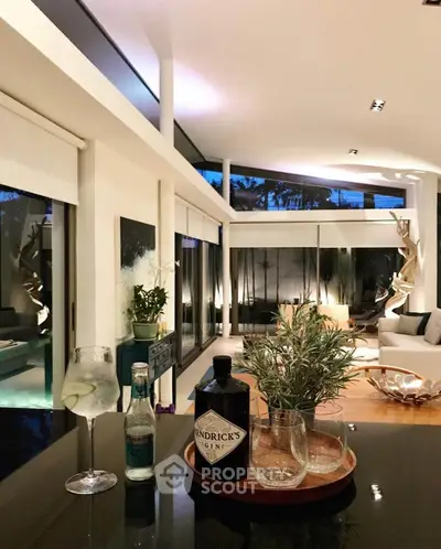 Luxurious modern living room with high ceilings and elegant decor, featuring a stylish bar setup and large windows.