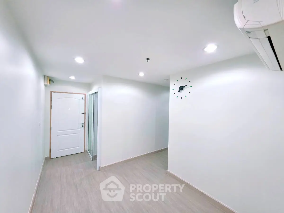Spacious modern hallway with sleek flooring and wall-mounted clock, perfect for contemporary living.