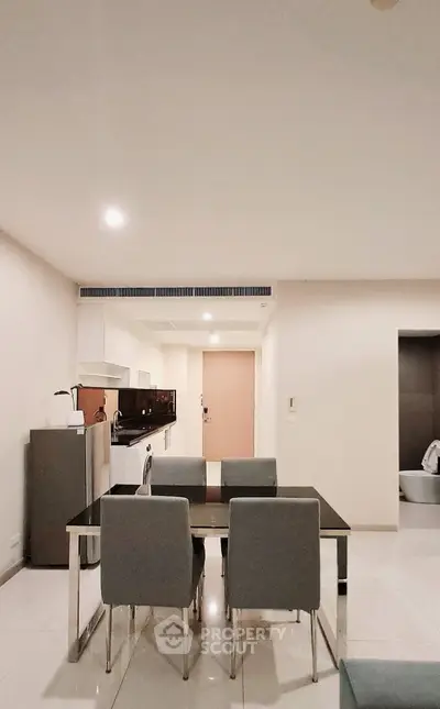 Modern dining area with sleek furniture and open kitchen layout in a contemporary apartment.