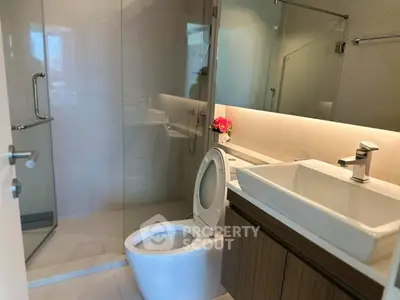 Modern bathroom with glass shower and sleek vanity in luxury apartment.