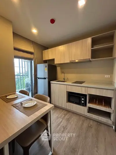 Modern kitchen with sleek cabinetry, built-in appliances, and dining area in a stylish apartment.