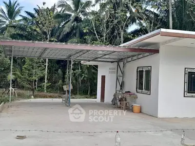 Charming single-story home with spacious carport and lush tropical surroundings.