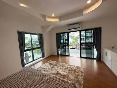 Spacious bedroom with large windows and balcony access, featuring modern design and ample natural light.