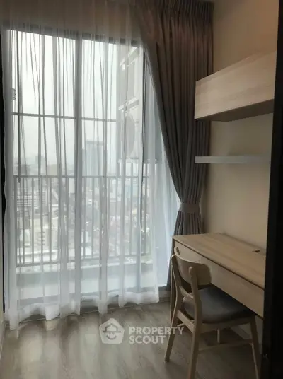 Cozy study nook with city view, featuring a wooden desk and chair by a large window with elegant curtains.