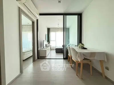 Modern apartment with open living and dining area, featuring sleek furniture and natural light.