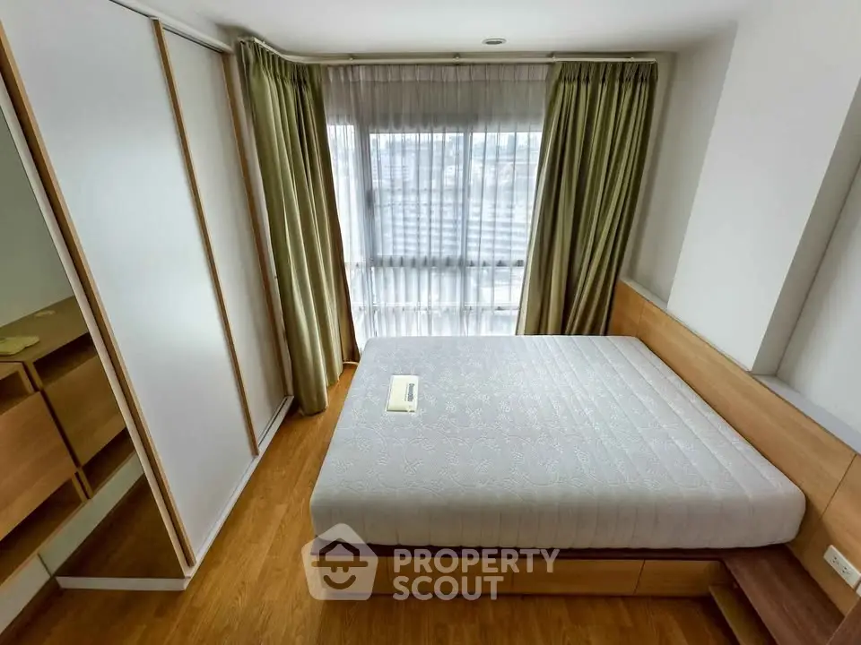 Spacious bedroom with large window and modern wooden furniture