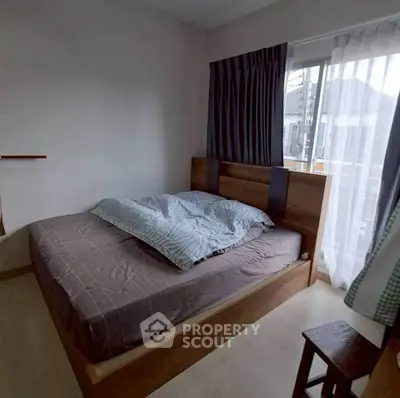 Cozy bedroom with large window and modern wooden bed frame, perfect for relaxation.
