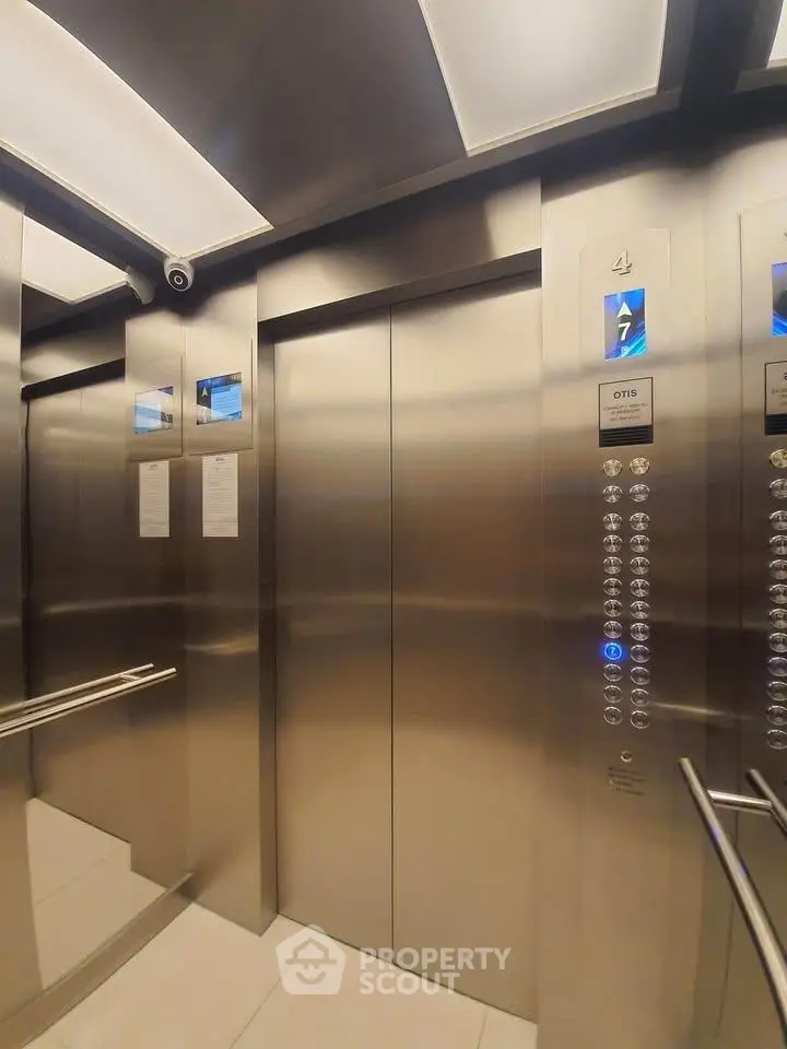 Modern stainless steel elevator interior with sleek design and illuminated control panel.