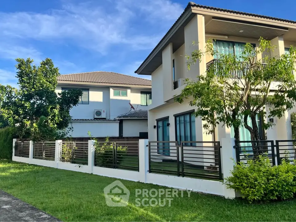 Modern two-story house with lush green lawn and sleek fence under blue sky.
