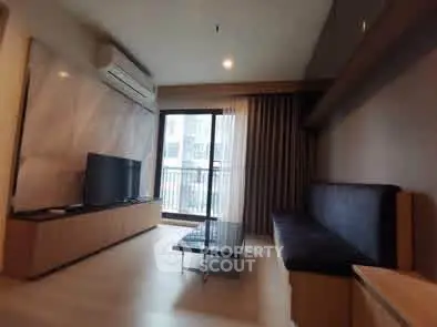 Modern living room with sleek furniture and large window offering natural light.