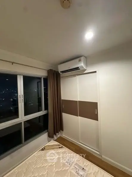 Modern bedroom with city view, featuring air conditioning and sliding closet doors.