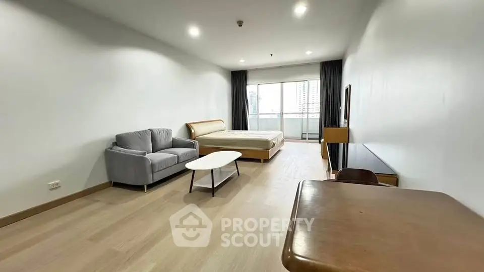 Spacious studio apartment with modern furnishings and large windows for natural light.