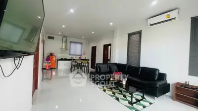 Modern living room with sleek black furniture and open kitchen layout