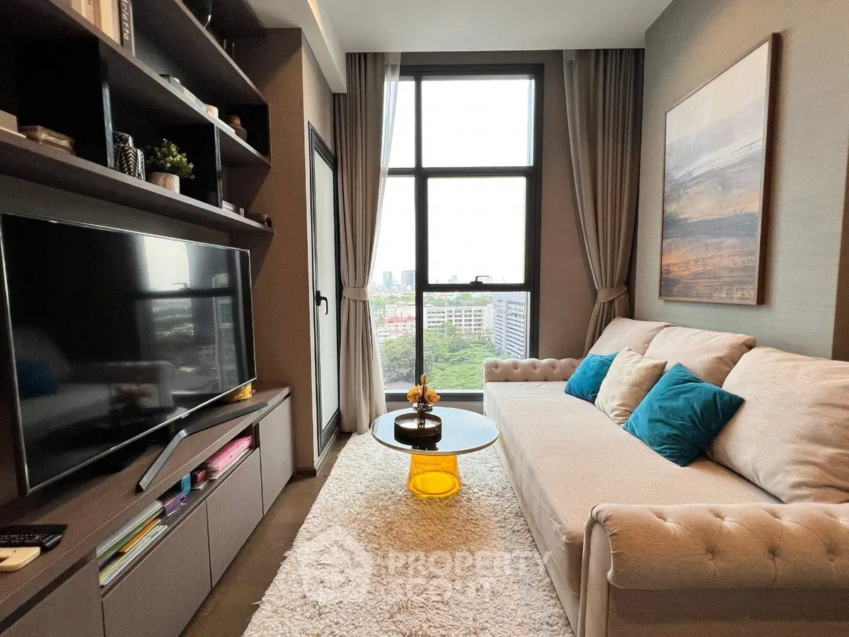 Cozy living room with modern decor and city view, featuring plush sofa and large TV.