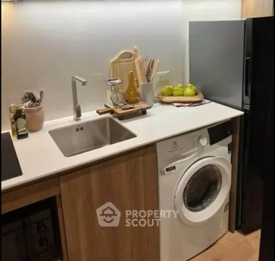 Modern kitchen with sleek appliances and integrated washing machine, featuring stylish wooden cabinetry.