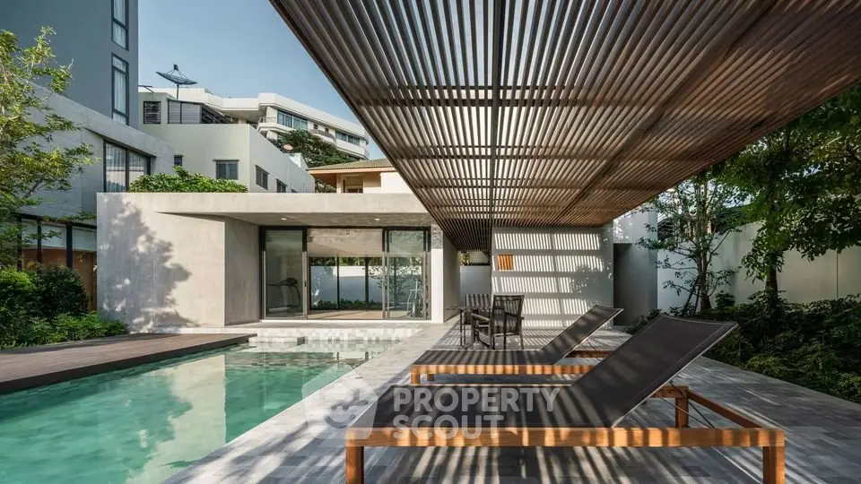 Luxurious modern home with sleek poolside lounge area and stylish pergola.