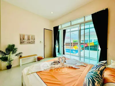 Spacious bedroom with pool view, modern decor, and natural light in a luxury home.