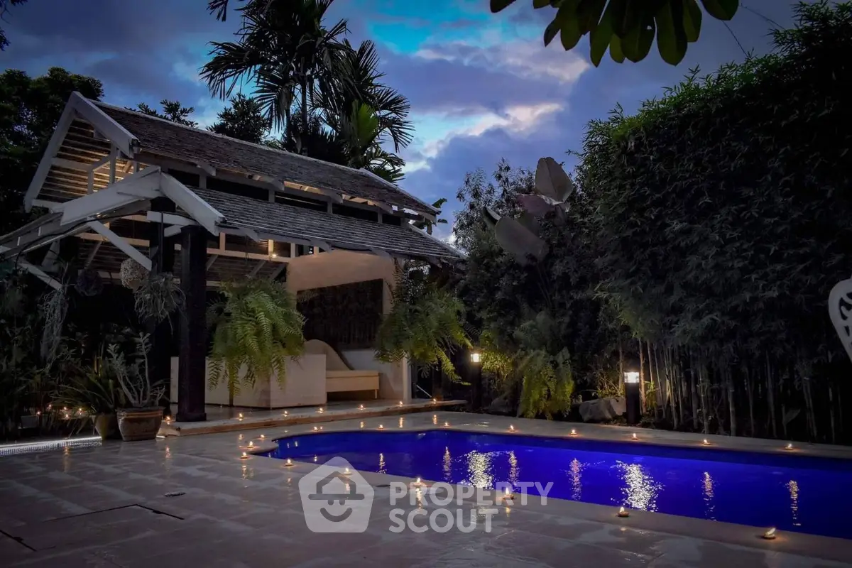 Luxurious tropical poolside retreat with ambient lighting and lush greenery.