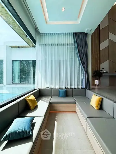Luxurious modern living room with large windows and stylish seating overlooking a pool.