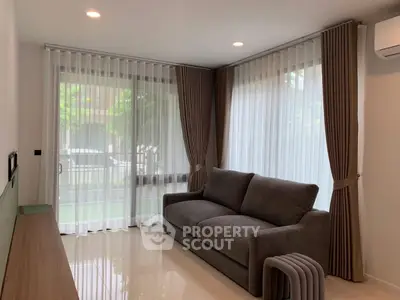 Modern living room with large windows and elegant curtains, featuring a comfortable sofa and stylish decor.