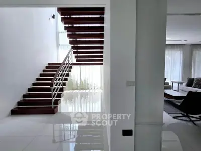 Modern interior with sleek staircase and spacious living area, featuring elegant design and natural light.