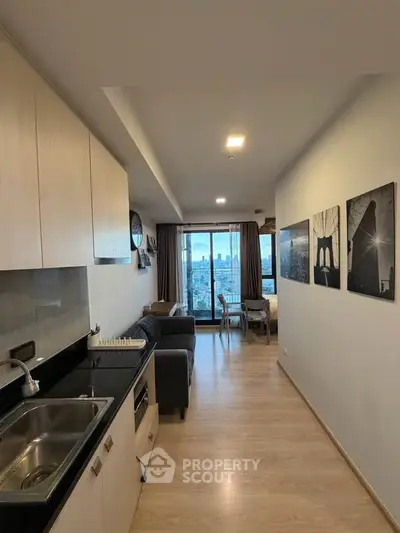 Modern open-layout kitchen and living room with city view balcony in high-rise apartment.