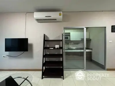 Modern living room with wall-mounted TV and air conditioning, adjacent to sleek kitchen.