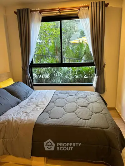 Cozy bedroom with large window and garden view, featuring elegant curtains and stylish bedding.