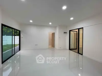 Spacious modern living room with large windows and glossy white flooring.
