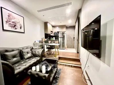 Modern living room with stylish black leather sofa and open kitchen layout