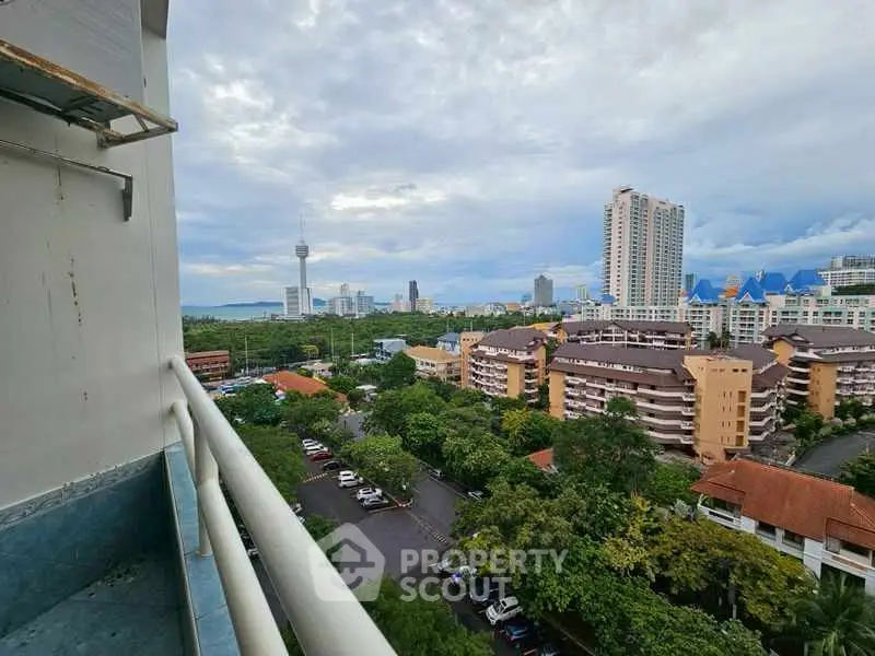Stunning cityscape view from high-rise balcony with lush greenery and urban skyline.