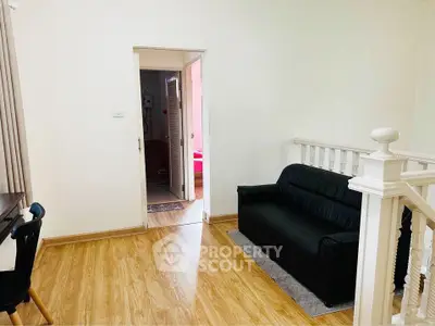 Cozy living area with black sofa and wooden flooring, perfect for relaxation.