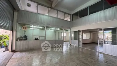 Spacious industrial-style interior with high ceilings and large windows, perfect for office or workshop space.