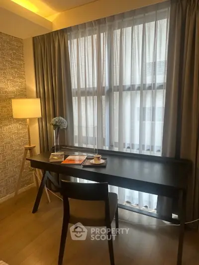 Cozy study area with elegant desk and chair by large window, perfect for productivity and relaxation.
