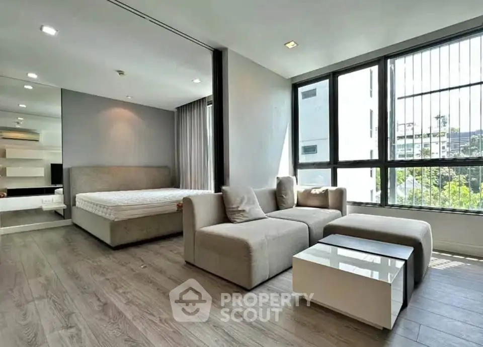 Modern studio apartment with large windows and stylish furnishings