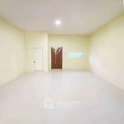 Spacious empty room with tiled floor and wooden door, ideal for customization.