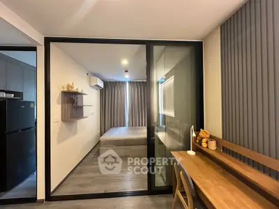Modern studio apartment with glass partition, cozy workspace, and sleek design.