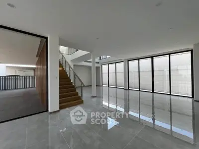 Spacious modern living room with large windows and sleek staircase