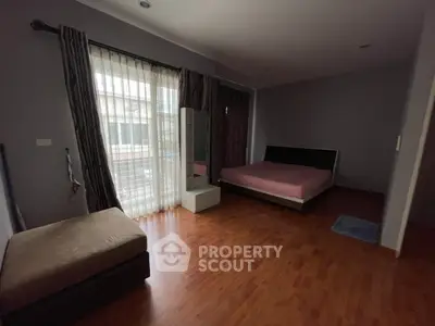 Spacious bedroom with wooden flooring and large windows for natural light.