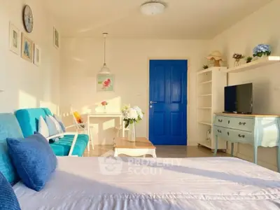 Charming bedroom with vibrant blue accents and cozy seating area, perfect for relaxation and comfort.