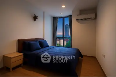 Cozy bedroom with modern decor and stunning city view from window.