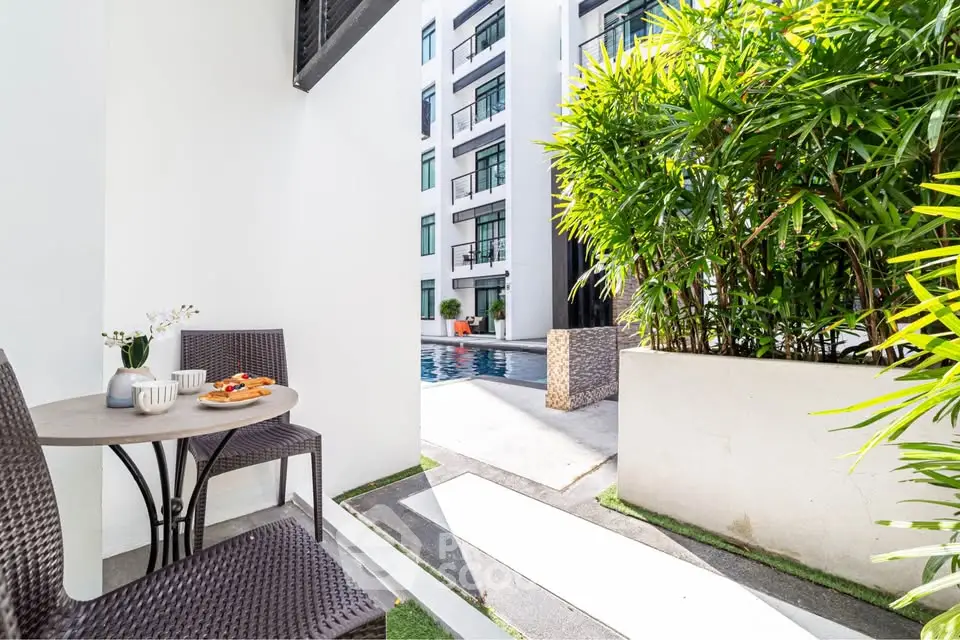 Charming poolside view from a cozy balcony with modern outdoor seating.