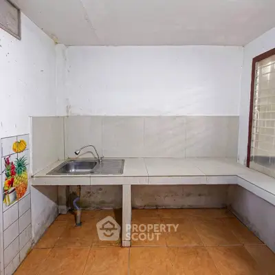 Basic kitchen with tiled countertop and sink, ideal for renovation opportunities.