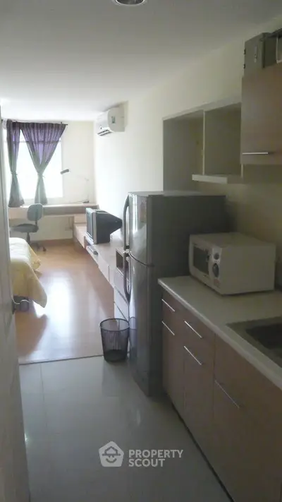 Modern studio apartment with kitchen and living area, featuring sleek appliances and natural light.