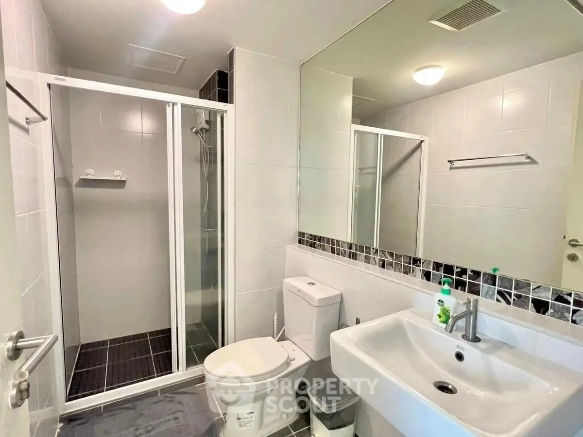 Modern bathroom with glass shower, sleek sink, and contemporary fixtures in a stylish apartment.