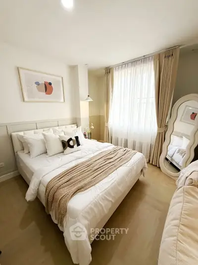 Cozy bedroom with elegant decor and natural light, featuring a stylish bed and modern artwork.
