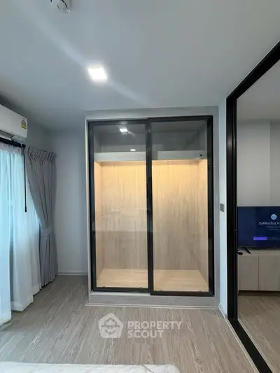 Modern bedroom with glass-enclosed walk-in closet and sleek wooden flooring
