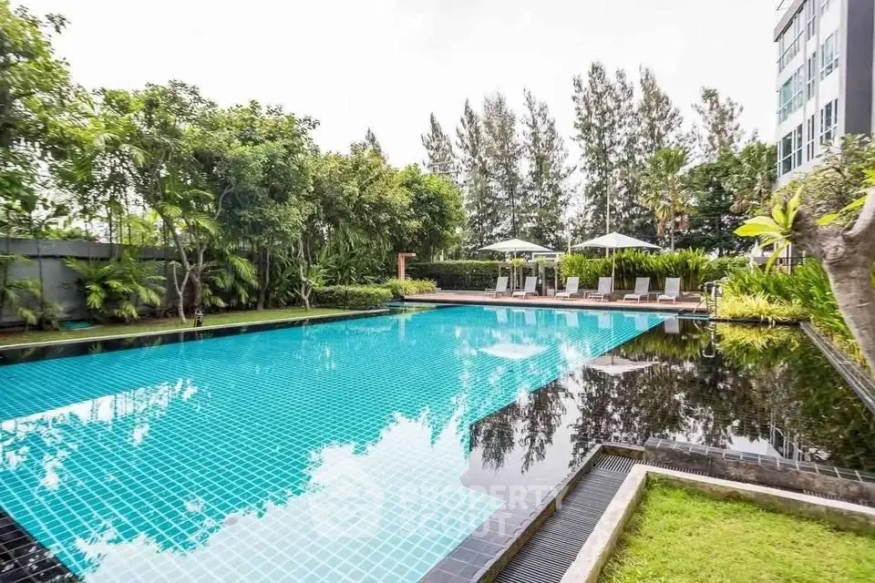 Luxurious outdoor pool surrounded by lush greenery in a modern residential complex.