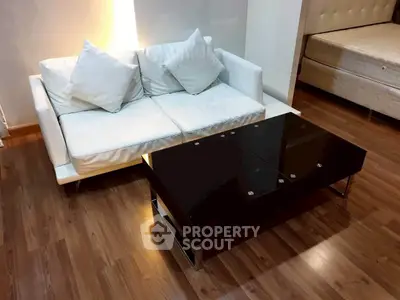 Modern living room with sleek black coffee table and white sofa on polished wooden floor.