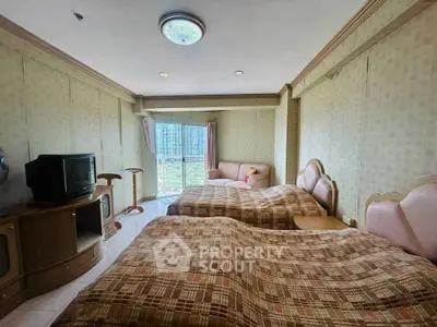 Spacious bedroom with twin beds and a cozy seating area, featuring a large window with a scenic view.